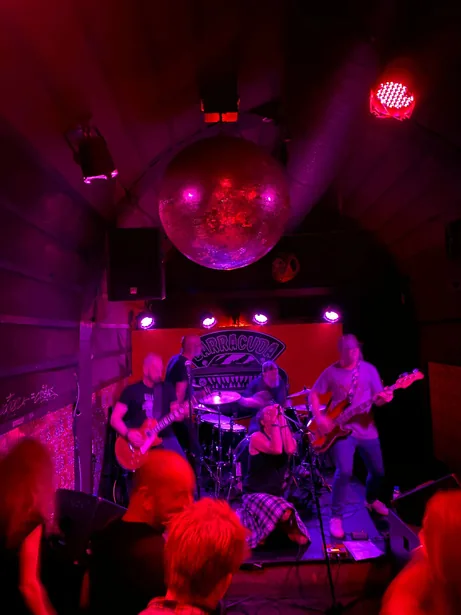 Palco da Bulha visto do fundo da sala, com luz vermelha e público em frente