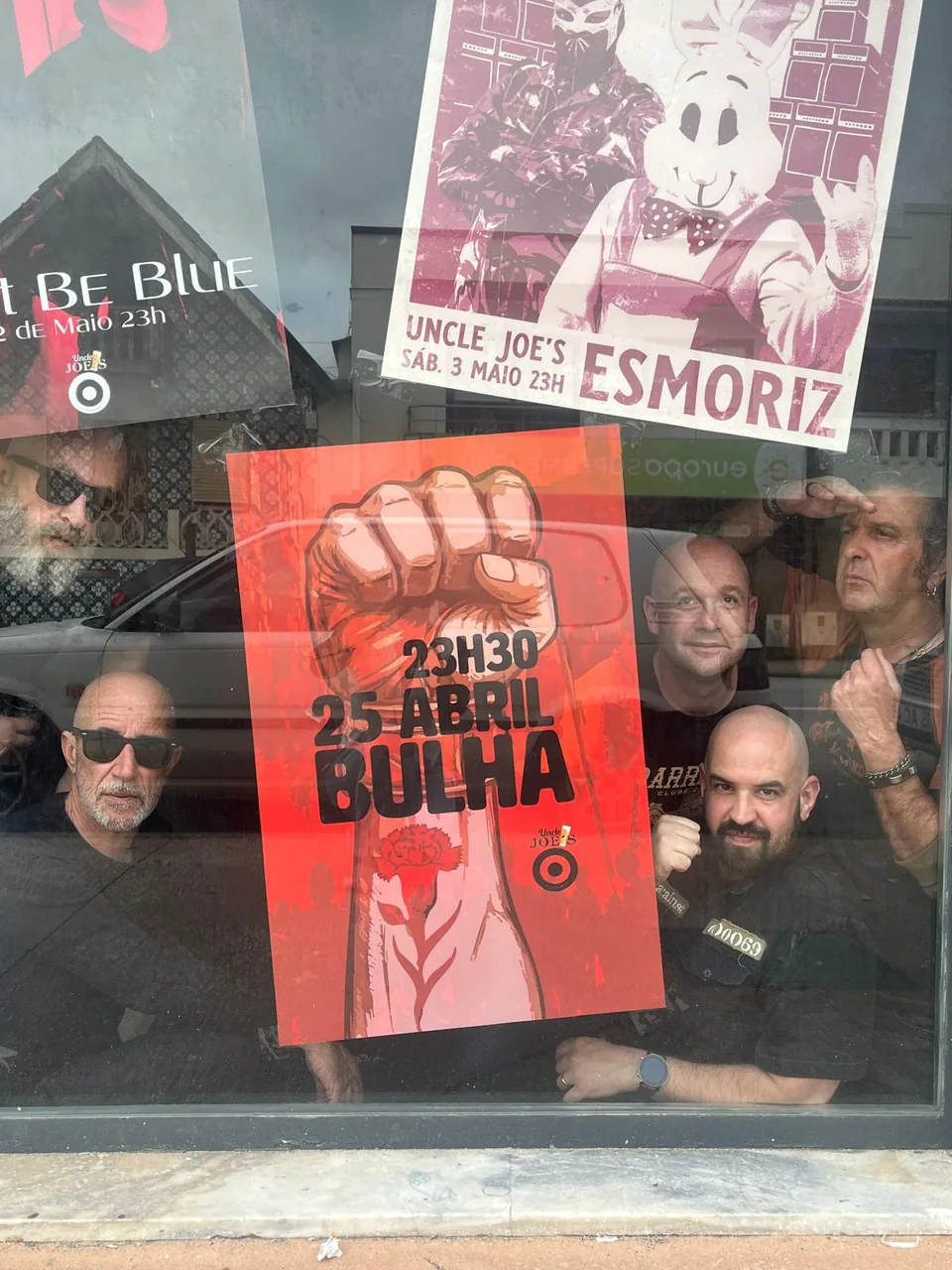 Membros da Bulha atrás do cartaz do concerto no Uncle Joe's, em Esmoriz